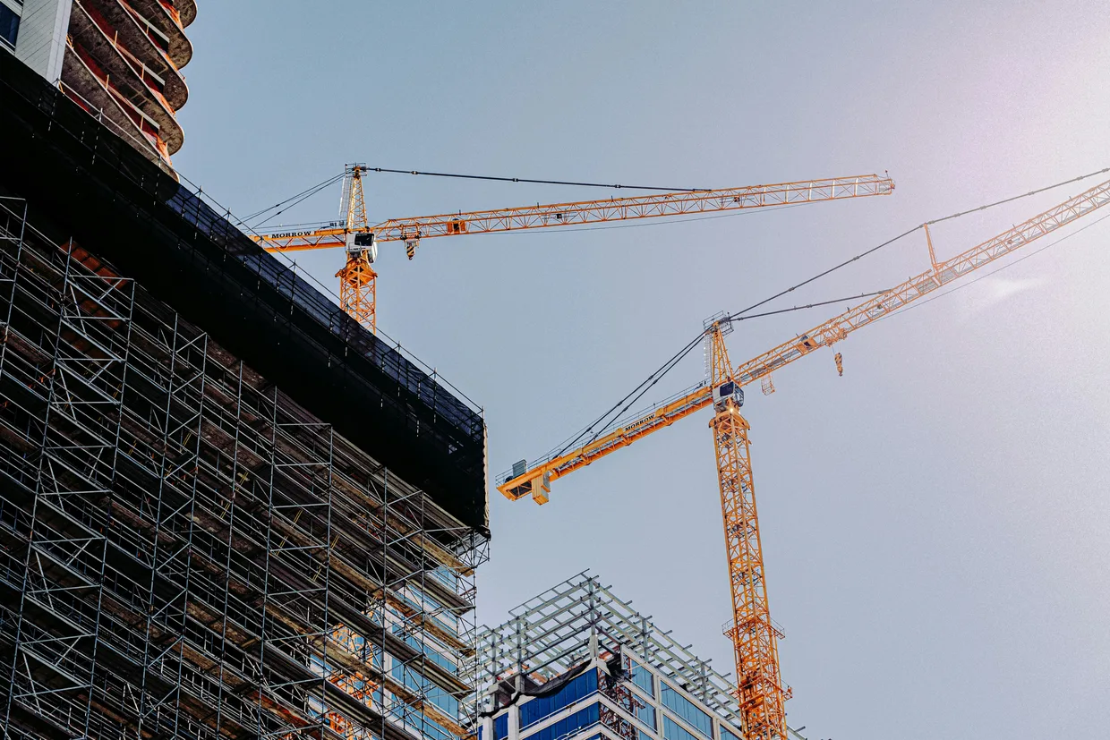 A tower crane over a building under construction, the frame up to several storeys with formwork still on the upper deck.
