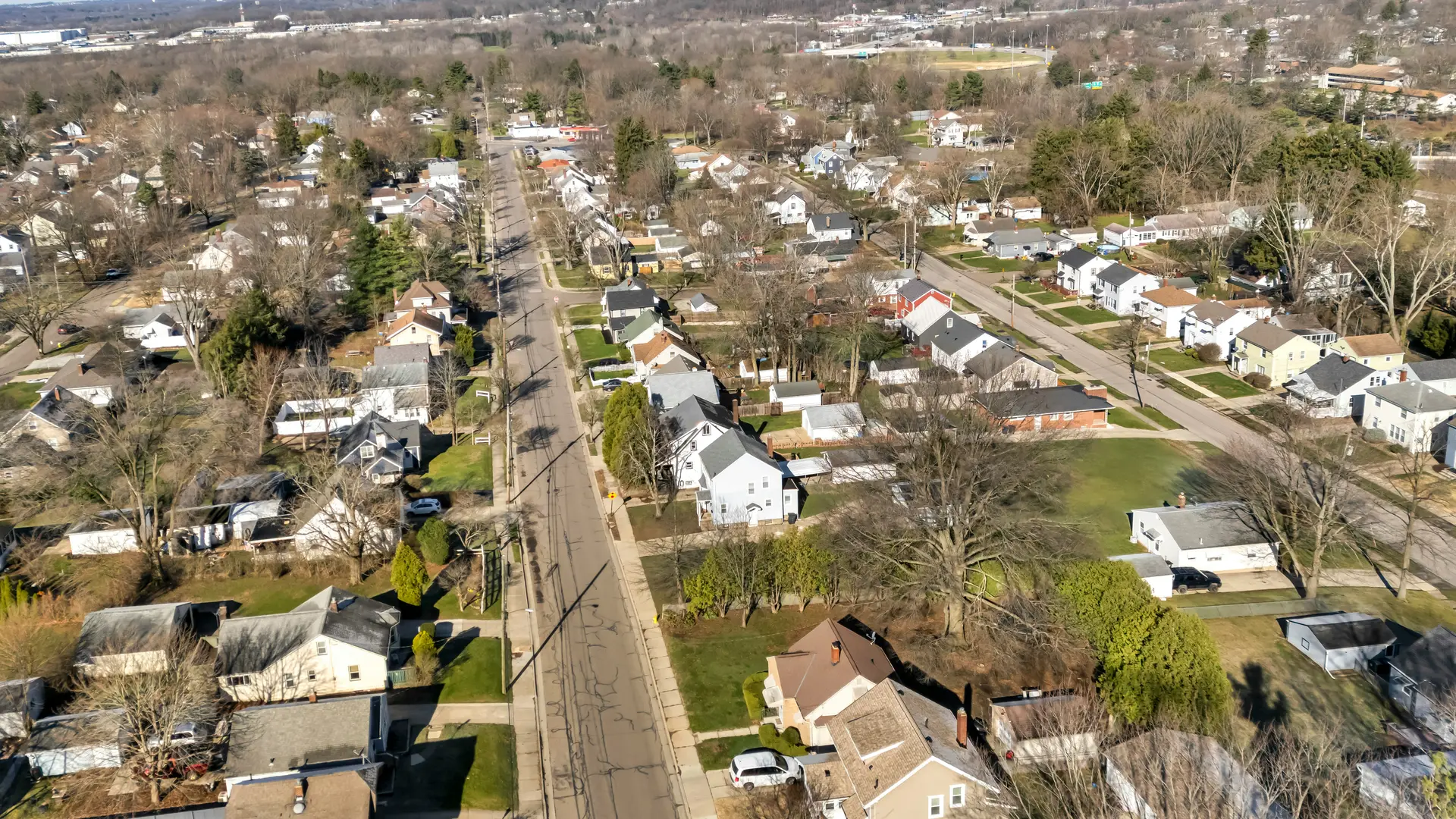 A residential neighbourhood from the air, a long street of detached houses on wide lots running to the horizon.